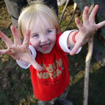 Child in Wildlife Watch t-shirt with muddy hands, Julie Norman