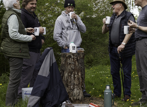 People drinking tea by a log