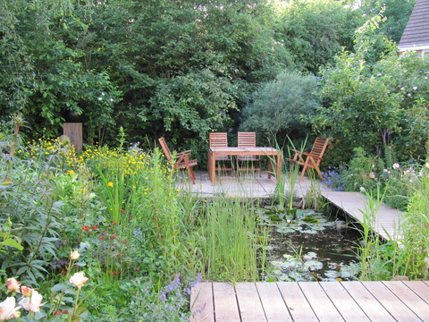 A small contemporary estate house garden with a wildlife pond at its heart, seating areas around and mixed native and ornamental planting perfect for the heavy clay soil.