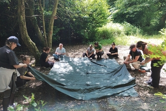 A group of forest school trainees learning how to put up a shelter sheet
