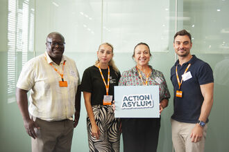 4 people stood together holding a sign that reads 'Action Asylum'