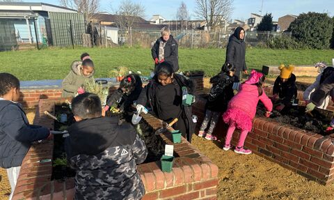 Children planting raised beds made of bricks in a community garden in Newport