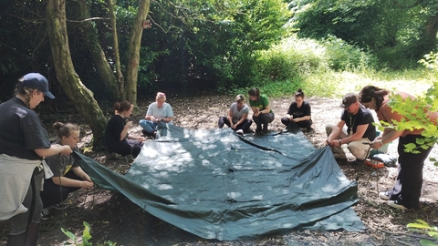 A group of forest school trainees learning how to put up a shelter sheet