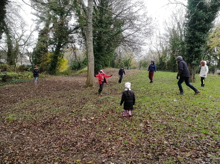 A blindfolded person is standing in the middle of a circle of trees as other group members try and sneak closer without being heard