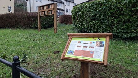 An interpretation board and a bee hotel on a patch of green space in Pontypool