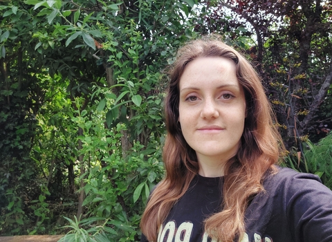 Katy smiling at the camera, with trees in the background