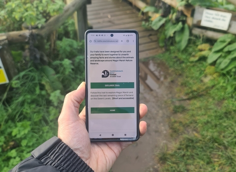 A phone in hand with nature reserve in background