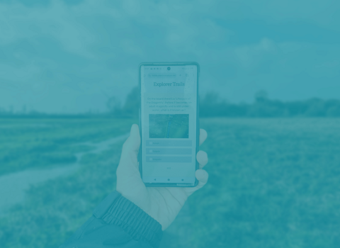 Blue coloured phone and a digital trail in a nature reserve